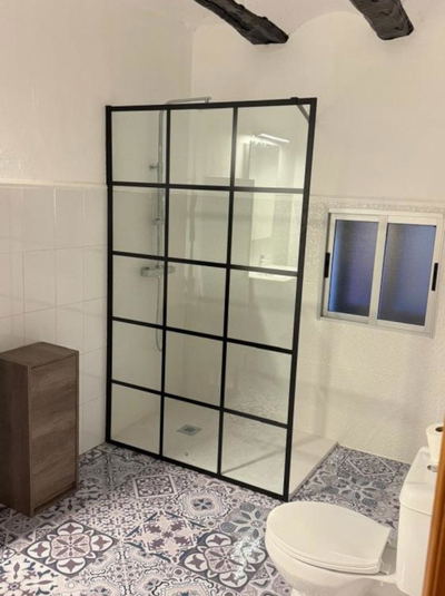 Mampara de ducha con cuadros negros instalada en baño industrial